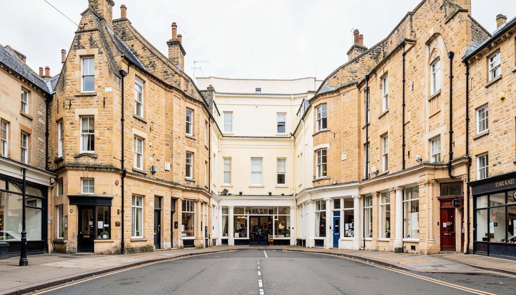 A clean architectural photograph of a British high street with strong symmetry, warm sandstone and cream facades under soft overcast light